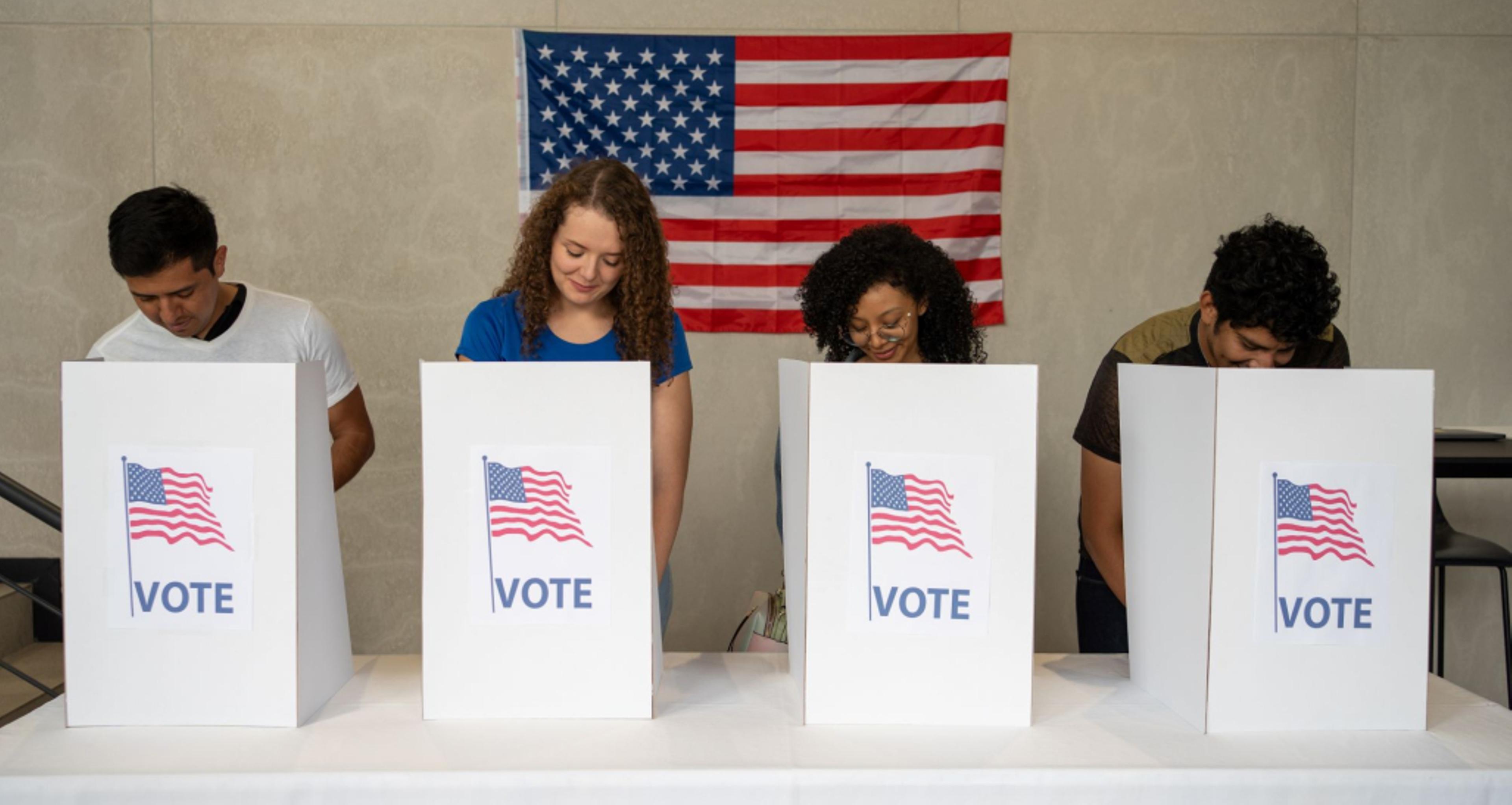 People voting standing in front of an American flag.