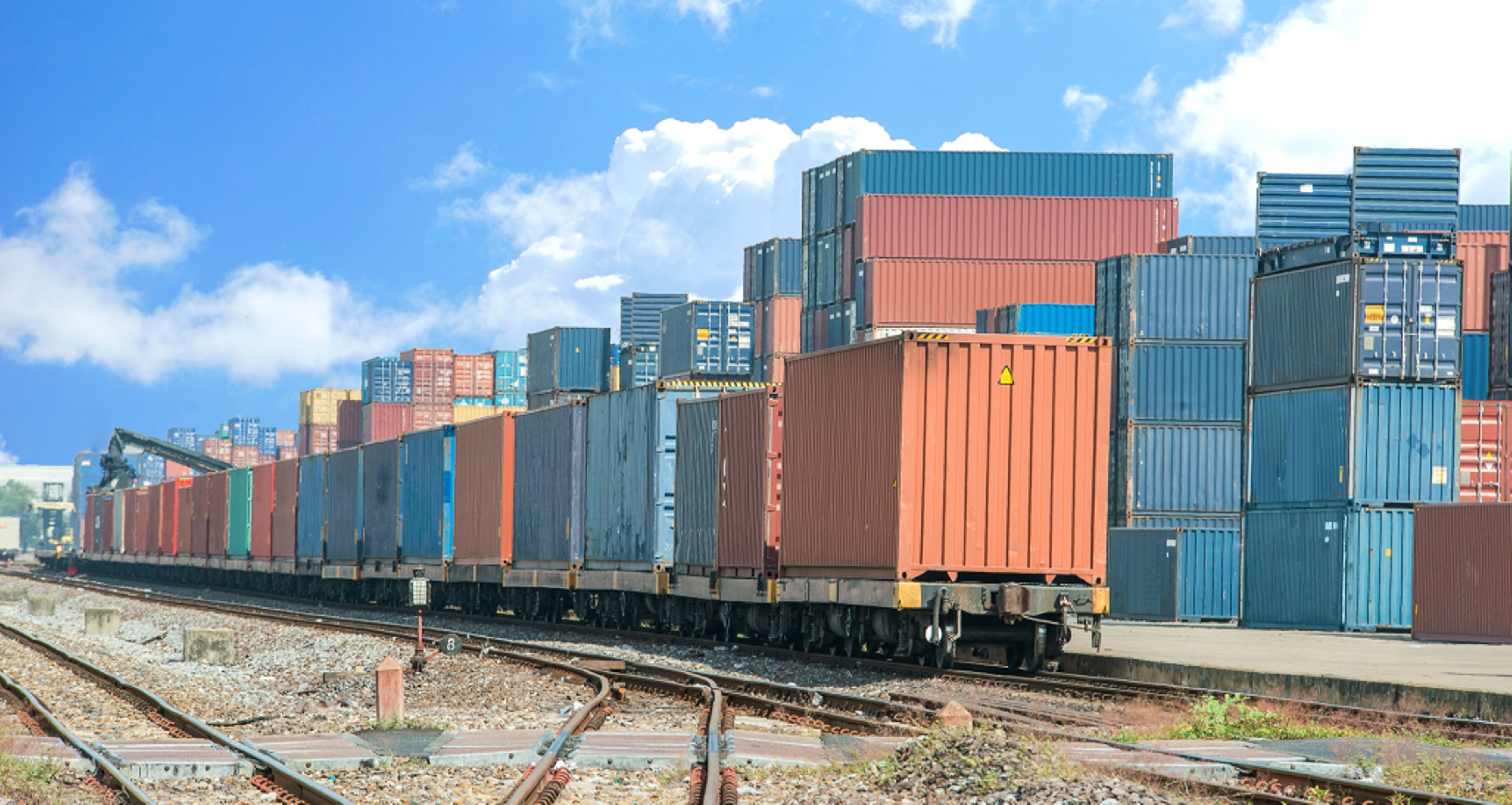 Shipping containers stacked by a railroad.