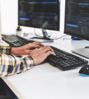 Someone typing on a desktop computer.